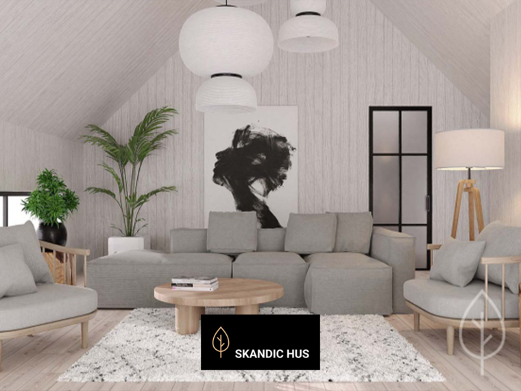Jasny salon na poddaszu domu Skandic 70, z wysokim dwuspadowym sufitem i ścianami wykończonymi jasnym drewnem. W centrum znajduje się szara narożna sofa, dwa fotele i okrągły drewniany stolik ustawiony na jasnym dywanie. Wnętrze uzupełniają rośliny doniczkowe, czarno-biały obraz, lampy wiszące i drzwi w czarnej ramie.